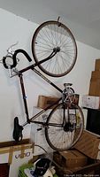 Side view of brown Schwinn World bicycle with drop handlebars and metal wheels hung on wall.
