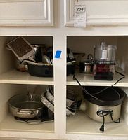 Shelved kitchen items including Cuisinart food processor, pots, slow cooker, and aluminum pans