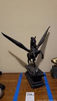 Front view of bronze Pegasus statue with wings spread showing rearing pose and rectangular base.