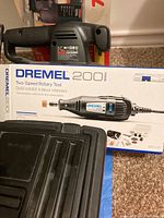 Dremel 200 Series box, rotary tool, and accessory case stacked with Skil jigsaw visible.