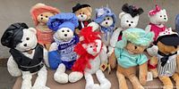 Group photo of 10 white plush Chantilly Lane musical bears dressed in a variety of colorful outfits, all seated together.