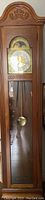 Photo of the large grandfather clock, showing wood casing, glass front, pendulum visible inside.