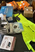 Whole lot showing ArcticX jumpsuit, plastic cups box, kid's tiger sleeping bag, lever hardware box, paper bags, and under pads package