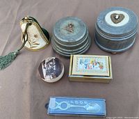 Lot of vintage miscellaneous music boxes and decorative items arranged on cloth background.