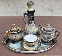 Front view of the vintage Japanese tea set on an oval tray showing dragon motifs, gold accents, and a small cup with saucer.