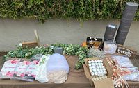 Display of wedding decorations on a brown tablecloth including fairy lights, flower garlands, wrapped backdrop tulle fabrics, boxes with candles and ribbons