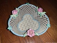 Top-down view of heart-shaped Belleek china basket showing lattice detail, pink roses, and blue edge accents.