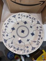 Top view of a large, scalloped edge dish with blue floral and grapevine pattern on a white ceramic background.