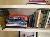 Shelf with assorted hardcover and paperback books related to history, geography, and flags, showing multiple titles.