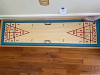 Top view of the shuffleboard showing the playing surface and scoring zones on wood board with blue fabric border.