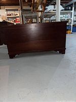 Side view of the closed wooden cherry cedar chest showing part of the rectangular shape and finish.