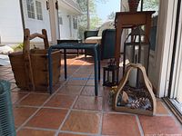 Image shows the wooden Chinese rice bucket and wicker foot stool on the tiled floor beside the sunroom windows with three lantern-style candle holders in view.