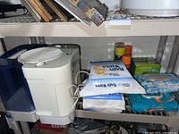 Photo of humidifier next to multiple unopened packs of baby wipes and spray cans on a shelf.