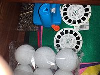 Photo of vintage blue Viewmaster viewer with two reels along with white foam balls and colorful felt sheets as background.