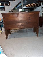 Front view of solid wood chest showing hinged top lid and legs.