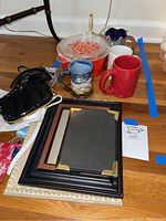 Vintage Pyrex casserole dish with lid, four coffee mugs and three picture frames on hardwood floor