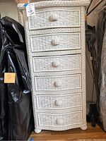 Front view of the white wicker shelf showing six drawers and its general size in relation to nearby items.