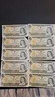 Front view of all ten Canadian one dollar bills arranged in two columns, showing consistent design featuring Queen Elizabeth II and bilingual denomination.