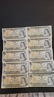 Ten 1973 Canadian one dollar bills arranged in two columns, front side showing Queen Elizabeth II and the Canadian coat of arms.