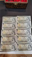 Ten Canadian one dollar bills dated 1974, arranged in two rows of five. Each bill features Queen Elizabeth II and is printed with serial numbers. The image shows the front side of the banknotes.