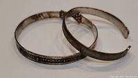 Two sterling silver cuff bracelets, one stacked inside the other showing overall size and design.
