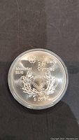 Front side of the silver coin showing Montreal 1976 Olympic logo, Olympic rings with laurel wreath, and 5 Dollars denomination.