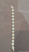 Full length view of the bracelet laid flat showing all the linked flower-shaped turquoise set segments.
