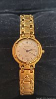 Front view of Krug Baumen women's gold-tone wristwatch showing the round dial, Roman numerals, and date window at 6 o'clock.
