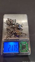 Photo of assorted scrap silver jewelry pieces on a digital scale showing the total weight of 21.75 grams.