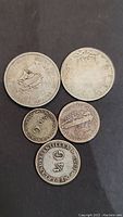 Front and back views of 5 silver coins displaying various inscriptions, designs, and denominations