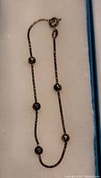 Full view of sterling silver bracelet with five spherical beads and a spring ring clasp displayed in a box.