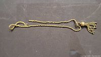 Full view of rope chain with tassel pendant laid flat