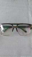 Front view of men's glasses showing black frame with gold tone detailing around the rectangular lenses and bridge.