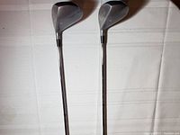 Three titanium oversized golf clubs shown from shaft side, heads visible at distance