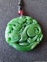 Front view of the green jade carved lion pendant showing detailed patterns and smooth finish