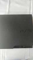 Top view of black PlayStation 3 Slim console showing PS3 logo and matte finish surface.