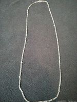 Full view of one silver Figaro link chain on black background
