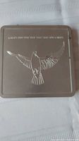 Closed metal case with embossed dove and millennium years on lid