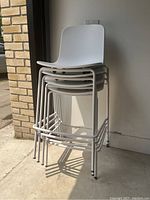 Stack of four white stools against wall, side view