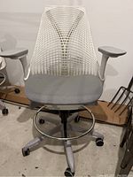 Front view of entire SAYL stool showing back, seat, arms, foot ring and base