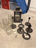 Full set featuring IKEA black metal lantern, six black metal candlesticks with wax residue, and six clear glass mason jars.