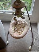 Full view of the Fisher-Price baby swing in soft fabric colors with attached mobile and sturdy metal frame.