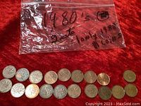 Two sets of Canadian pennies from the 1980s displayed on a red surface with a labeled plastic bag indicating '1980's 2 sets 1 only 1988 18 coins.' Coins show circulated wear.