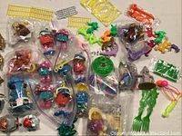 Photo showing an assortment of colorful small collectible plastic toys including Funny Fry Friends and other characters in sealed bags and loose around.