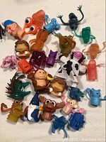 Several small colorful plastic toys including animals, finger puppets, and pencil toppers