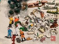 Miniature animal and human figurines displayed on a flat surface showing variety of species and poses