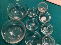 Top view of 9 clear glass bowls arranged on a surface, showing variety of sizes.
