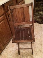 Front view of antique wooden folding chair showing vertical slats and wooden frame with visible wear.