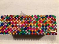 Top and angled view of the multicoloured beaded rectangular tissue box cover showing bead detail and brand label.