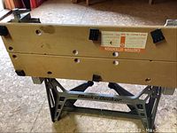 View showing the Black & Decker logo on the saw horse metal frame with wooden top surfaces and corner plastic caps.